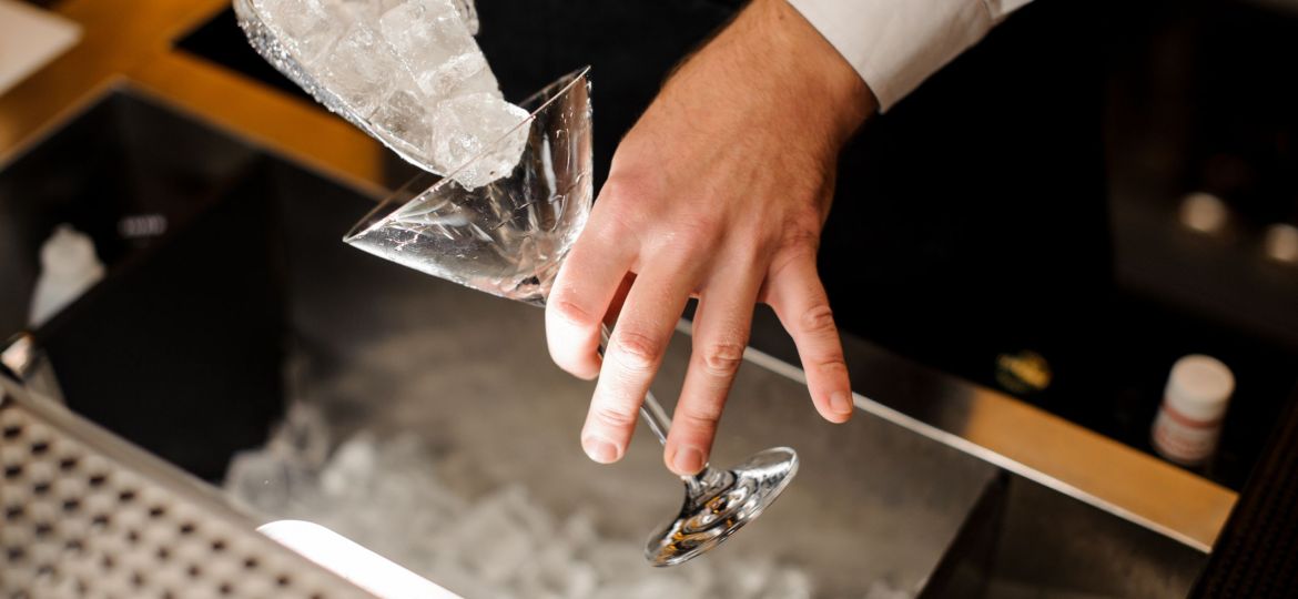 Bartender pouring ice cubes into the cocktail glass